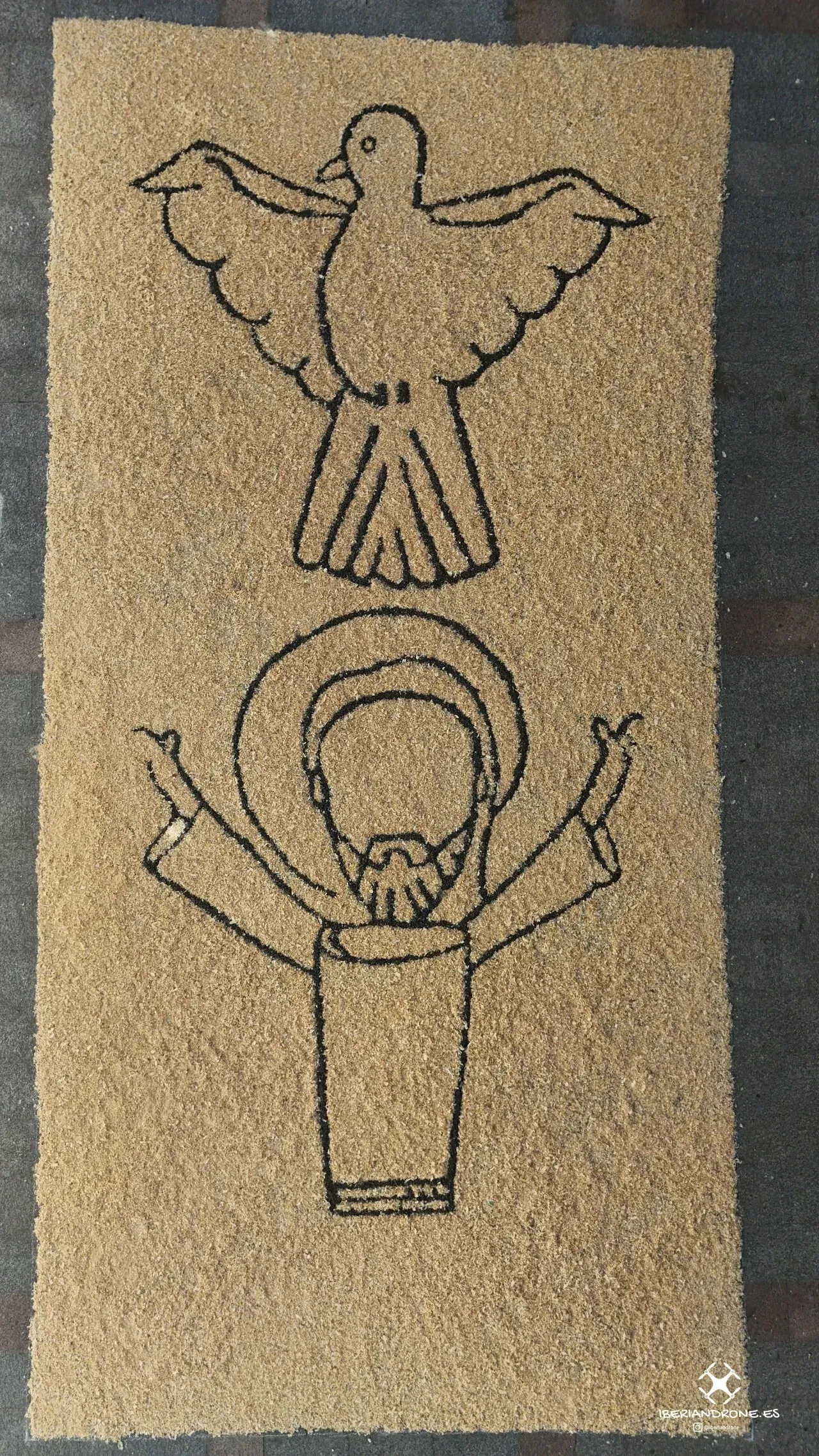 Detalle de una alfombra con la paloma del Espíritu Santo, vista desde arriba.