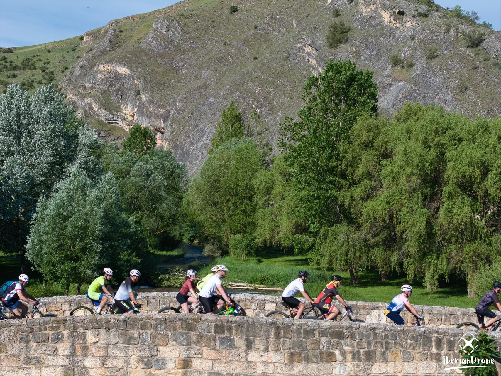 Ciclistas cruzando un puente de piedra durante la Carrera Nískalo 2026, vistos con dron