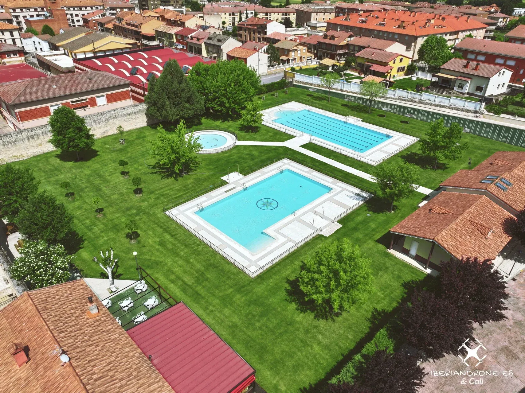 Las piscinas entre el césped y los árboles, con el casco urbano de El Burgo de Osma alrededor.