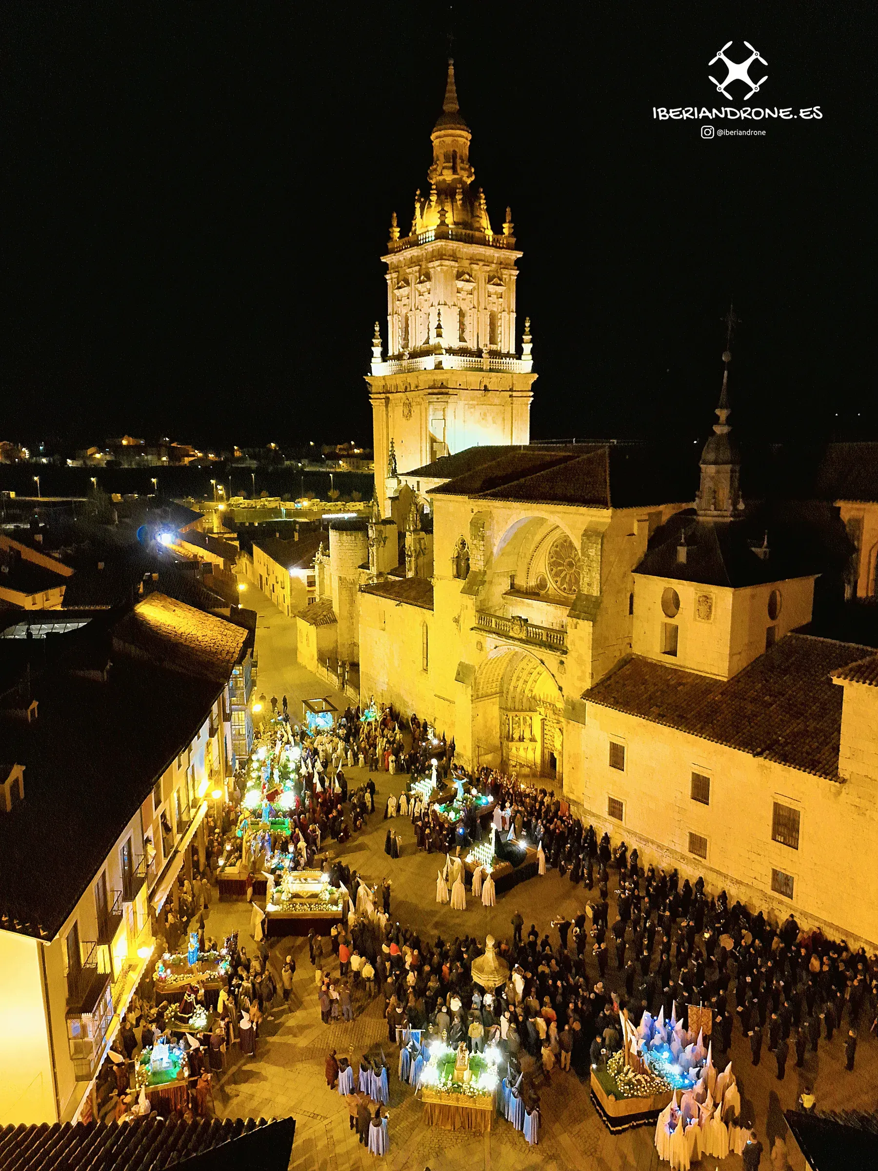 La catedral de El Burgo de Osma iluminada y la procesión llenando la plaza en la noche del Viernes Santo de 2024, vista con dron